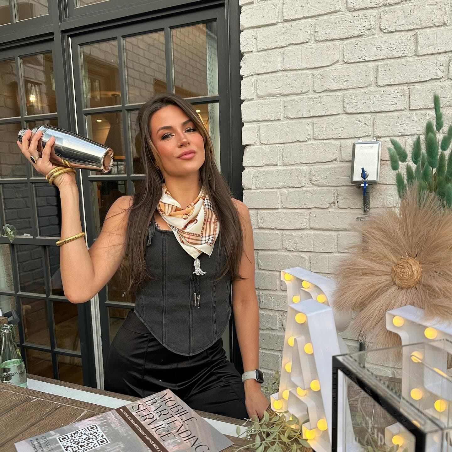A Tipsy Boot bartender shaking a cocktail behind a lit bar setup